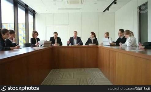 Business people at corporate meeting sitting around table and talking