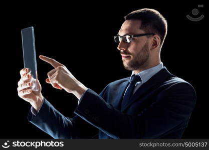 business, people, augmented reality and modern technology concept - businessman in suit working with transparent tablet pc computer over black background. businessman in suit with transparent tablet pc