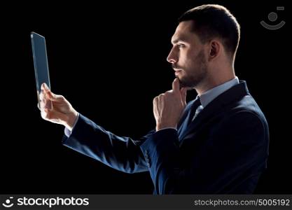 business, people, augmented reality and modern technology concept - businessman in suit working with transparent tablet pc computer over black backgrouns. businessman in suit working with transparent tablet pc
