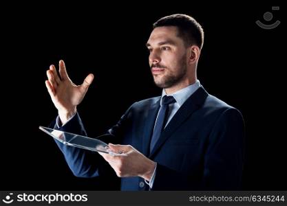 business, people, augmented reality and modern technology concept - businessman in suit working with transparent tablet pc computer over black backgrouns. businessman in suit working with transparent tablet pc