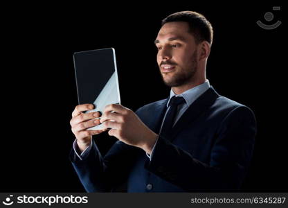 business, people, augmented reality and modern technology concept - businessman in suit working with transparent tablet pc computer over black background. businessman in suit with transparent tablet pc