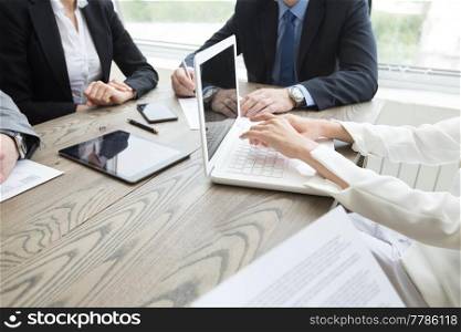 Business people brainstorming at office desk, analyzing financial reports and working with laptops and tablets. Business people brainstorming at office desk