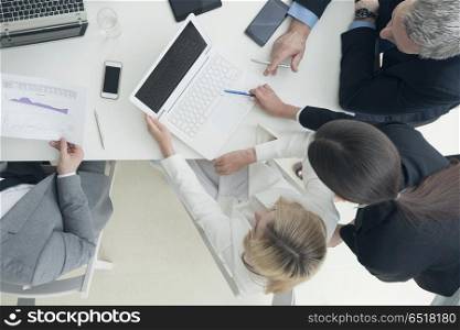 Business people brainstorming at office desk. Business people brainstorming at office desk, analyzing financial reports and working with laptops and tablets
