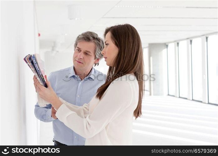 Business people choosing color samples against wall in empty office