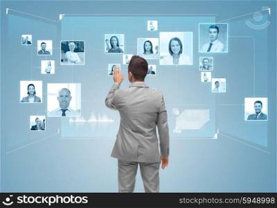 business, people, communication and social network concept - businessman touching contacts icons on virtual screen from back over blue background