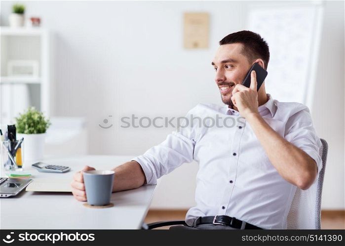business, people, communication and technology concept - happy businessman with laptop drinking coffee and calling on smartphone at office. businessman calling on smartphone at office