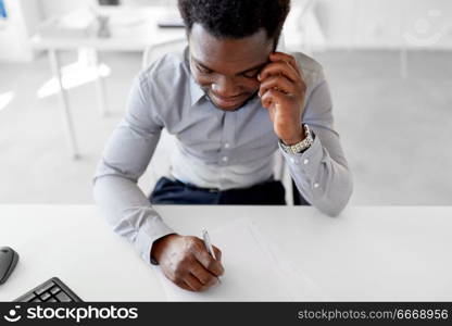 business, people, communication and technology concept - smiling african american businessman with papers calling on smartphone at office. businessman calling on smartphone at office. businessman calling on smartphone at office