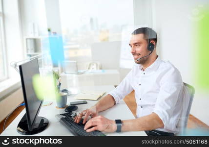 business, people, communication and technology concept - smiling businessman or helpline operator with headset and computer typing at office. businessman with headset and computer at office