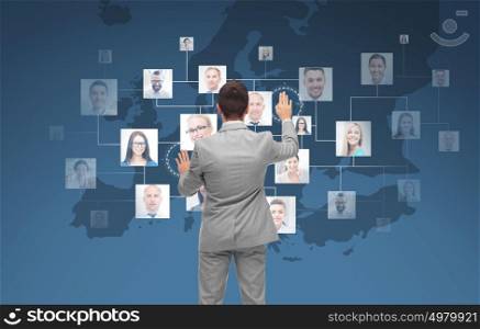 business, people, communication, cooperation and technology concept - businessman touching virtual screen with contacts icons and europe map over blue background. businessman using virtual screen with contacts