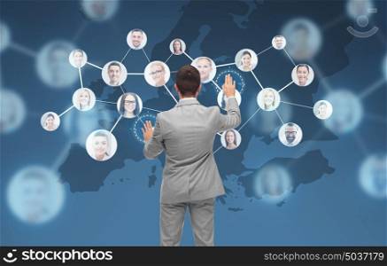 business, people, communication, cooperation and technology concept - businessman touching virtual screen with contacts icons and europe map over blue background. businessman using virtual screen with contacts