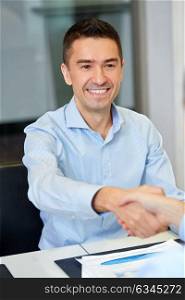business, people, cooperation, and partnership concept - smiling businessman making handshake gesture at office. smiling businessman making handshake at office
