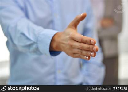 business people, cooperation, partnership and deal concept - close up of businessman making handshake gesture at office. businessman making handshake at office