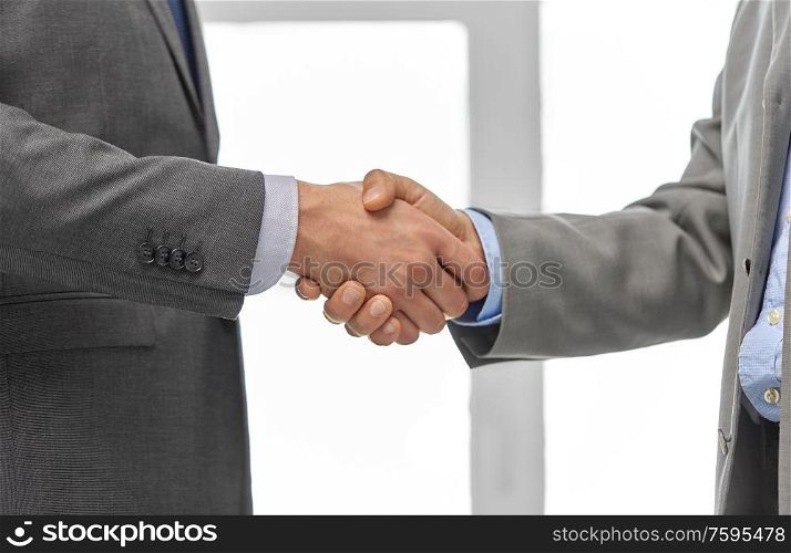 business people, cooperation, partnership and deal concept - close up of businessmen making handshake at office. close up of businessmen making handshake at office