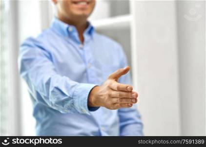 business people, cooperation, partnership and deal concept - close up of smiling businessman making handshake gesture at office. smiling businessman making handshake at office