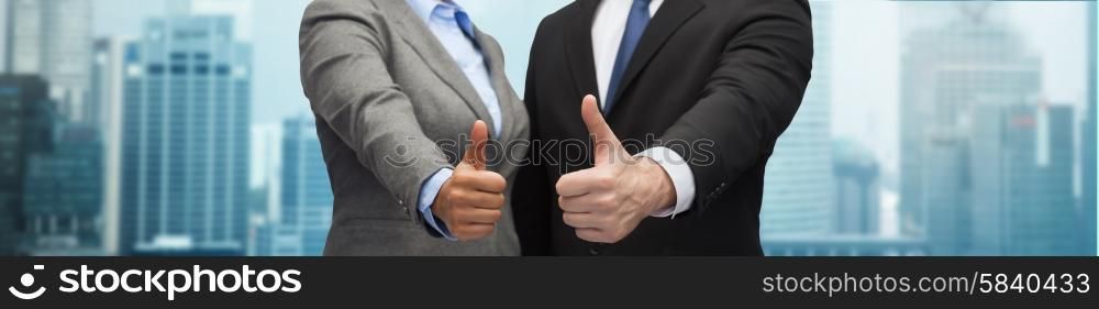 business, people, cooperation, success and gesture concept - businessman and businesswoman showing thumbs up over city background