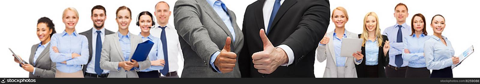 business, people, cooperation, success and gesture concept - businessman and businesswoman showing thumbs up over group of office team background
