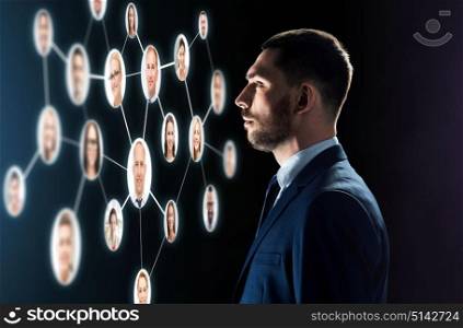 business, people, corporate, headhunting and technology concept - businessman in suit looking at contacts network over black background. businessman looking at contacts network