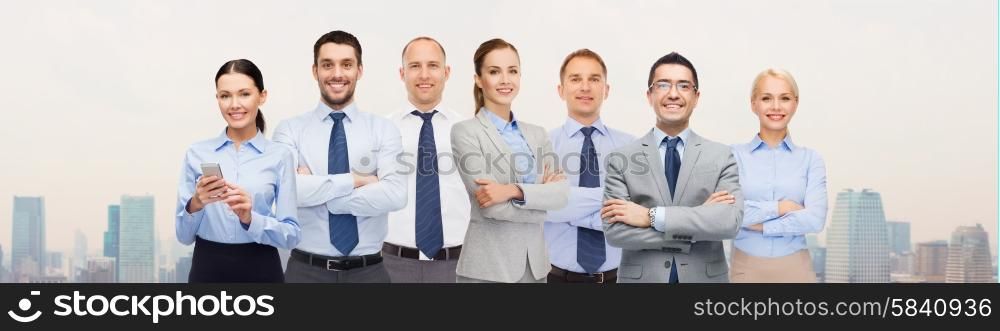 business, people, corporate, teamwork and office concept - group of happy businesspeople with crossed arms over city background