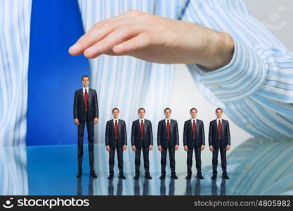 Business people covered with palm. Male hand protecting business people of different size