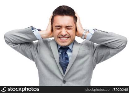business, people, crisis and emotional pressure concept - businessman in suit covering his ears by hands