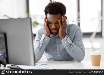 business, people, deadline and technology concept - stressed african american businessman with papers and computer working computer at office. stressed businessman with papers at office. stressed businessman with papers at office