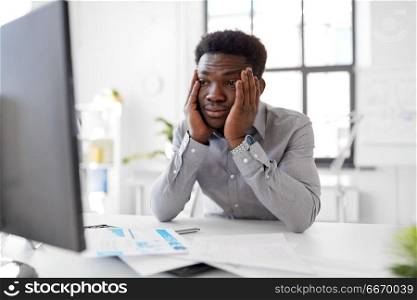 business, people, deadline and technology concept - stressed african american businessman with computer and papers at office. stressed businessman with computer at office. stressed businessman with computer at office