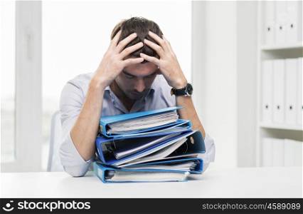 business, people, deadline, stress and paperwork concept - sad businessman with stack of folders at office