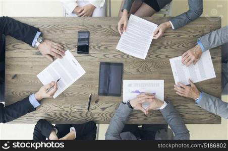 Business people discuss contract. Business people discuss contract sitting around office table, top view