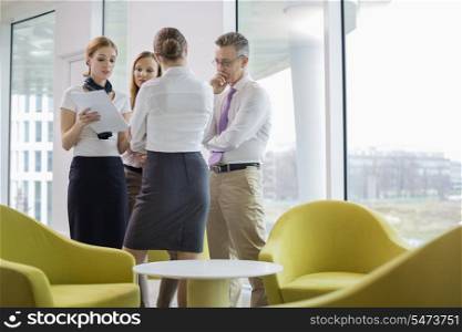 Business people discussing over documents in lobby