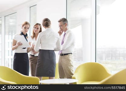 Business people discussing over documents in office lobby