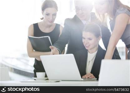Business people discussing over laptop in office cafeteria