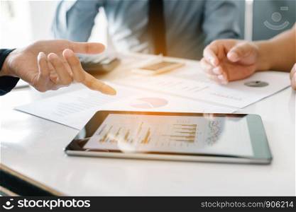 Business people examining financial reports working on desk and analyzing business growth on tablet