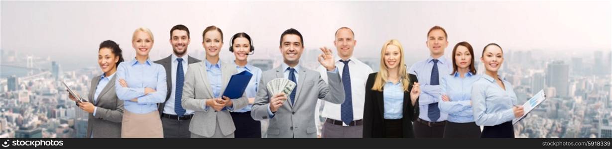 business, people, finances and banking concept - group of happy businesspeople with money bags over city background