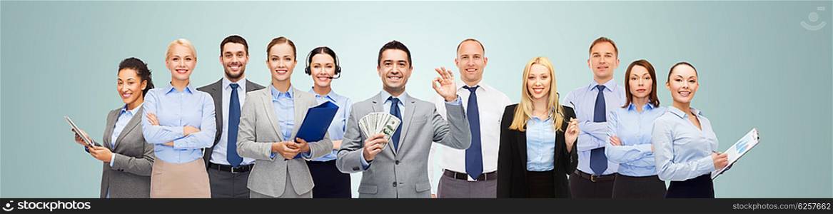 business, people, finances and banking concept - group of happy businesspeople with money bags over blue background
