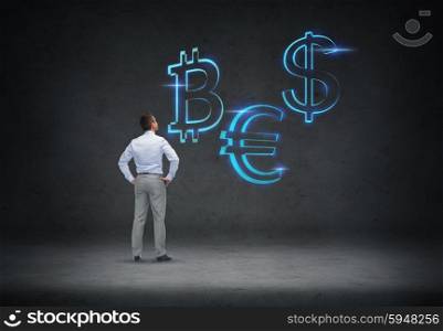 business, people, finances and money concept - businessman looking at currency symbols over concrete room background from back