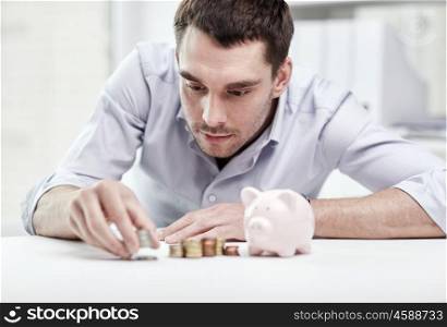 business, people, finances and money saving concept - businessman with piggy bank and coins at office