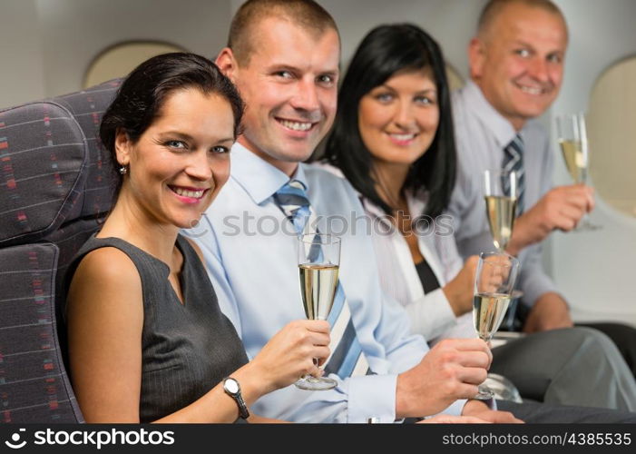 Business people flying airplane drink champagne smiling at camera