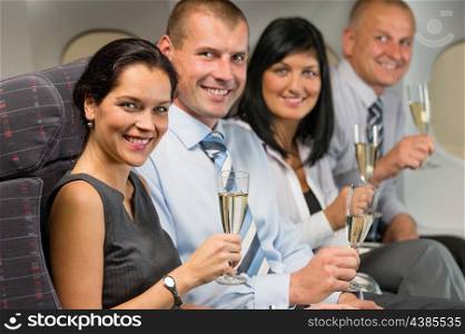 Business people flying airplane drink champagne smiling at camera