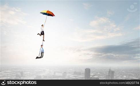 Business people flying in the sky on umbrella. Escape from office