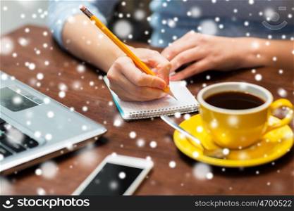 business, people, freelance and lifestyle concept - woman writing to notebook with pencil at office over snow