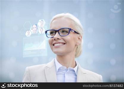 business, people, future technology and communication concept - young smiling businesswoman in eyeglasses with virtual screen, video chat and charts projection outdoors