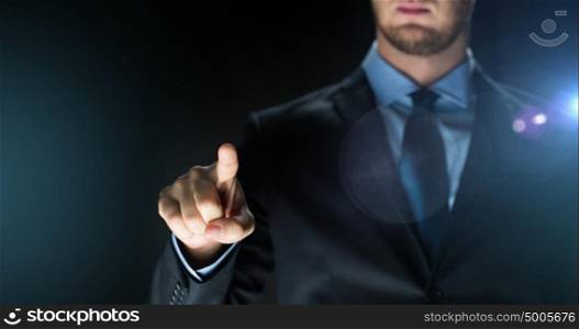 business, people, future technology and cyberspace concept - close up of businessman in suit touching something imaginary over dark background and lens flare. businessman touching something imaginary