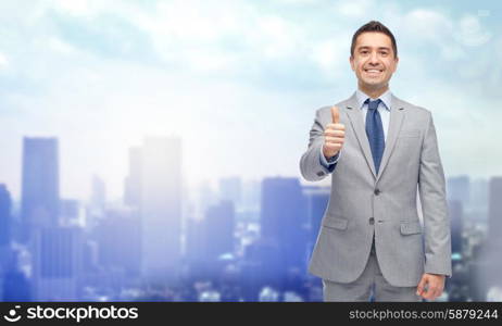 business, people, gesture and success concept - happy smiling businessman in suit showing thumbs up over city background