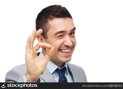 business, people, gesture and success concept - happy smiling businessman in suit showing ok hand sign