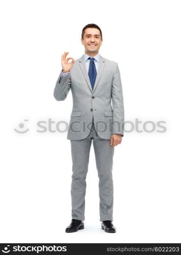 business, people, gesture and success concept - happy smiling businessman in suit showing ok hand sign