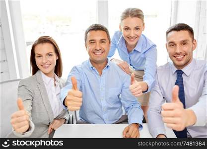 business people, gesture and success concept - happy smiling creative team showing thumbs up at office. happy business team showing thumbs up at office