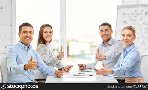 business people, gesture and success concept - happy smiling creative team showing thumbs up at office. happy business team showing thumbs up at office