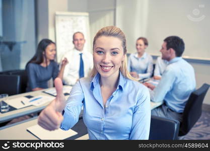 business, people, gesture and teamwork concept - smiling businesswoman showing thumbs up with group of businesspeople meeting in office