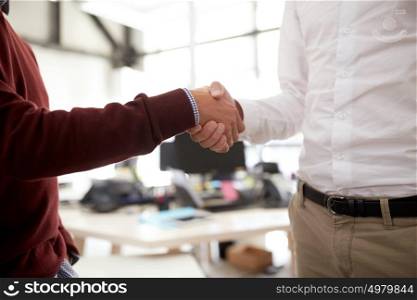 business, people, gesture, cooperation and partnership concept - businessmen making handshake at office. businessmen making handshake at office