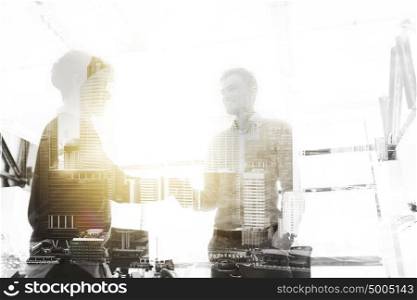 business, people, gesture, cooperation and partnership concept - happy businessmen making handshake at office over urban double exposure effect. happy businessmen making handshake at office